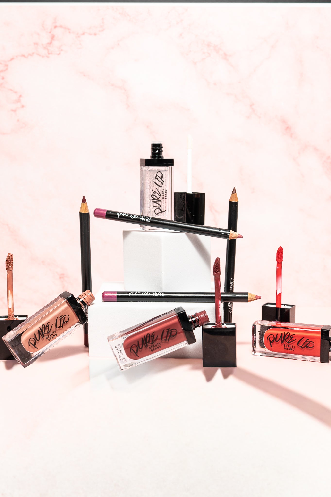 Collection of lip products including lipsticks and lip glosses on a light pink background